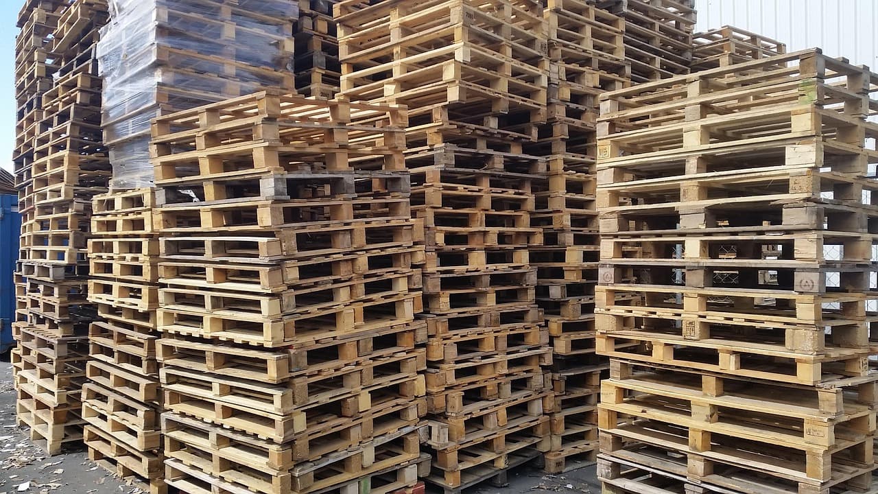 Des palettes en bois empilées dans une zone logistique.